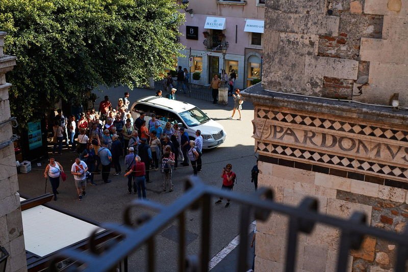 The inlaid lava-stone façade of Palazzo Corvaja, seen from a balcony of the Inn